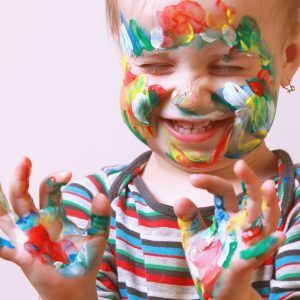 niña riendo con la cara y las manos pintada